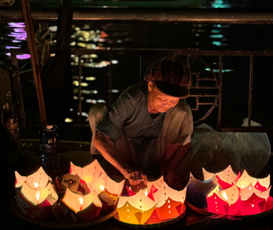 old lady lighting lanterns on a bridge