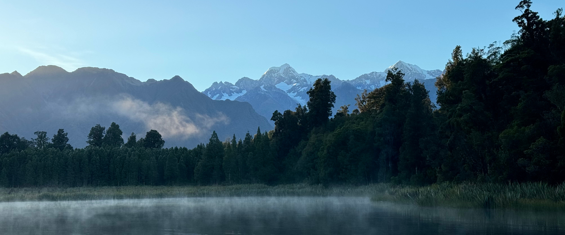 Lake Matheson with Mount Cook and other mountains in the background. Sunrising and fog on the waters